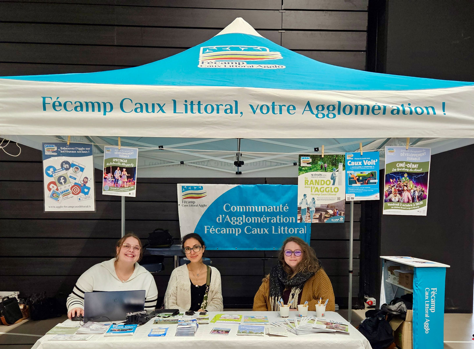 Stand d'information de l'Agglomération Fécamp Caux Littoral lors d'un forum, trois personnes derrière une table de brochures